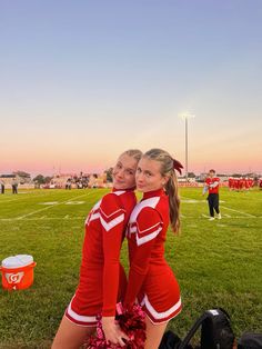 two cheerleaders posing for the camera at a football game