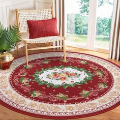 a red and white rug with flowers on it in front of a chair next to a window