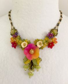 We call this color Caliente with its colorful tones of purple, yellow, red, fuchsia and lime. This necklace has a central flower with clusters of smaller flowers that are either polymer clay or hand painted resin. They are all hand beaded together with 3 tiny ball drops all hand beaded with seed beads. The chain it self is also hand beaded. Original, stunning Colleen Toland work of art. This is a quality piece of jewelry that will last a life time. Created by designer Colleen Toland who has been Paper Jewellery, Painted Resin, Ball Drop, Plastic Crafts, Paper Jewelry, Life Time, Small Flowers, Flower Necklace, Hand Beading