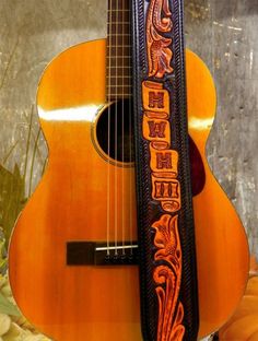 an orange guitar case sitting on top of a wooden table next to a flower arrangement