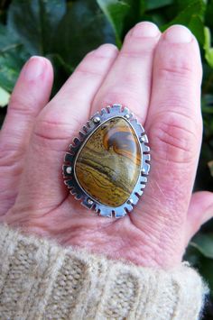 Made with a 18x24 mm natural, painted jasper cabochon, this ring reminds me of Western fields and open roads. The sandy colored gem sits on a 25x34mm base that is adorned with an unique pattern and sterling silver beads. The gem is wrapped in fine silver (.999) and sits on a sterling silver (.925) base. The stone possesses hues of chocolate brown, golden brown and black. The piece has been oxidized and lightly polished giving it great contrast and an industrial vibe. The piece is weighty and ric Unique Jasper Ring Jewelry, Unique Jasper Rings For Gift, Southwestern Jasper Jewelry Gift, Handmade Jasper Rings As Gift, Handmade Jasper Rings As A Gift, Handmade Jasper Rings For Gift, Desert Jasper, Open Roads, Painted Desert