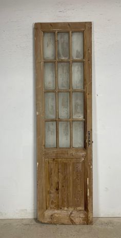 an old wooden door with glass panes on the front and side panels, against a white wall