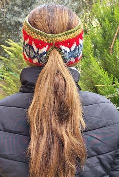 a woman with long hair wearing a knitted headband in front of some trees