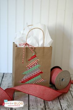 a brown paper bag sitting on top of a wooden table next to a roll of red ribbon