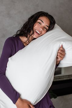 a woman is smiling while holding a pillow