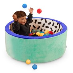 a young boy is playing in an inflatable pool filled with balls and toys