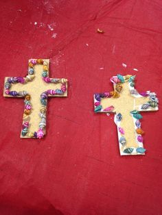 two wooden crosses sitting on top of a red cloth covered table next to each other