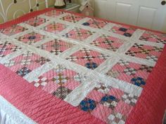 a bed with a pink quilt on top of it