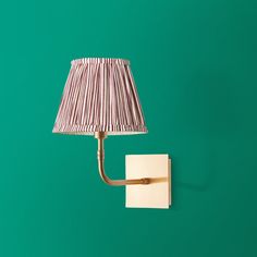 a lamp that is on the wall next to a green wall with a white shade