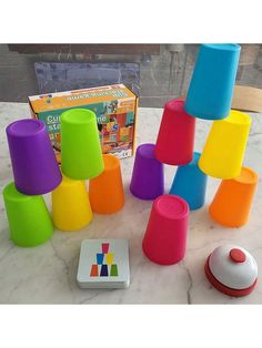 a group of different colored cups sitting on top of a marble table next to a game box