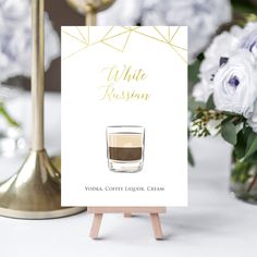 a card with a cup of coffee sitting on top of a table next to flowers