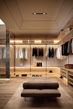 a large walk in closet with clothes hanging on the walls