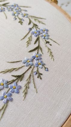 a close up of a cross stitch with blue flowers on it