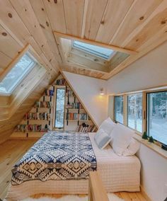 an attic bedroom with a bed and bookcases on the walls, along with two windows