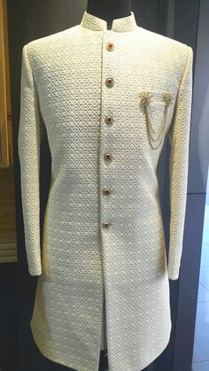 a white jacket with gold buttons on the lapel and collar is sitting on a mannequin's head