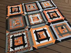 an orange and black quilt on a wooden deck