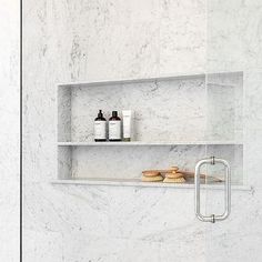 a bathroom with white marble walls and shelves