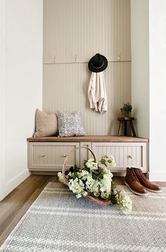 a bench with some flowers and a hat on it next to a wall mounted coat rack