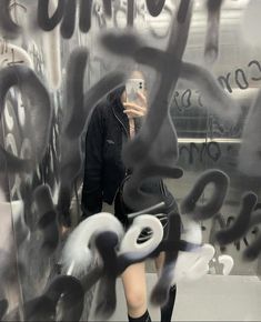 a woman taking a selfie in front of graffiti