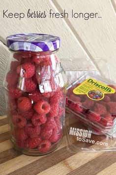 some raspberries are in a glass jar and on the table is a plastic bag