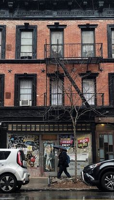 a man walking down the street in front of an apartment building with graffiti on it