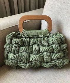 a green purse sitting on top of a couch next to a wooden handle and seat