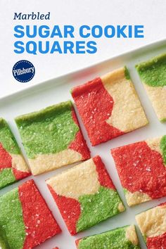 square shaped sugar cookie squares with green and red frosting on top, sitting on a white plate