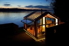 a lit up house sitting on the edge of a body of water