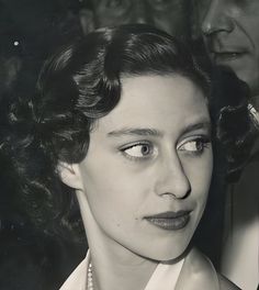 an old black and white photo of a woman with pearls on her necklace looking at the camera