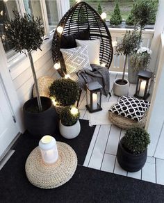 a porch with potted plants and lights on the side of it is decorated in black and white