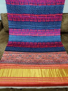 a blue and yellow blanket sitting on top of a couch