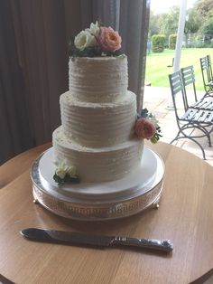 a three tiered cake sitting on top of a wooden table next to a knife