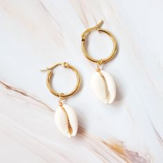 Huggie hoop earrings hung with real cowry shells—you'll want them on every beachy day. These are wrapped free-form with golden wires and inspired by the beauty of the pristine Waialea beach shores. Feel form wrapped cowry seashells Gold huggie hoop earrings Size: 1" W x 2" L Earrings are made from metal & real seashells Seashells are unique and made by mother nature, no two are alike Jewelry pouch included (color may differ) In interests of hygiene and for your protection, we cannot accept returns on earrings. White Hoop Earrings For Vacation, White Small Hoop Earrings For Beach, White Beaded Hoop Earrings For Beach, White Small Hoop Jewelry For The Beach, Adjustable Small Hoop Earrings For Vacation, Handmade Shell Hoop Earrings For Summer, Adjustable Small Hoop Jewelry For Beach, Hoop Earrings For Beach With Pierced Ears, Handmade Small Hoop Earrings For Vacation