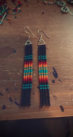 two pairs of beaded earrings sitting on top of a wooden table