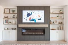 a living room with a fireplace, shelves and a flat screen tv on the wall