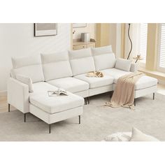 a living room with a white sectional couch and footstool in front of a window