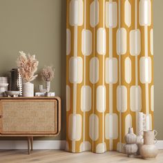 a living room with a yellow and white patterned curtain next to a wooden cabinet in front of it