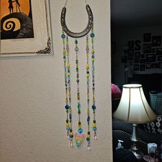 there is a wall hanging with beads on it and a lamp next to the wall