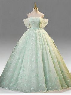 Celebrate elegance in this Mint Green Evening Dress, designed to exude sophistication and grace at every turn. Crafted from layers of soft, mint green tulle, this gown is adorned with exquisite floral appliqués that cascade down its length, adding depth and enchantment to the fabric's gentle flow. The bodice features a structured corset that cinches at the waist, creating a flattering silhouette that celebrates the fullness of plus-size figures. This corset is not only a nod to classic style but also ensures a perfect, tailored fit, enhancing comfort and confidence. The dress's romantic off-shoulder design, complemented by airy butterfly sleeves, frames the neckline beautifully, adding a touch of delicate charm. Flowing effortlessly to a floor-length finish, the skirt swirls with every ste Soft Green Wedding Dress, Elegant Light Green Wedding Gown, Mint Green Ball Gown, Light Green Princess Dress, Green Proncess Dress, Fairy Tail Dress Green, Light Green Wedding Dress, Green Tulle Princess Dress, Wedding Dress With Green