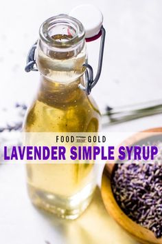 lavender simple syrup in a glass bottle next to a wooden spoon with lavender sprinkles