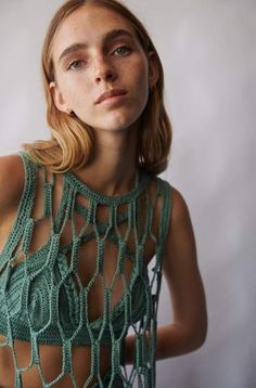 a woman with blonde hair wearing a green crochet top