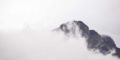 the top of a mountain is obscured by clouds