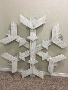 a snowflake made out of wooden planks sitting on the floor next to a wall