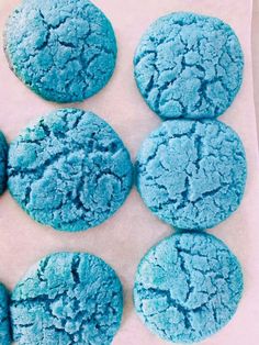 blue cookies are arranged on a piece of parchment paper