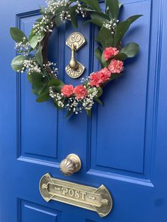 a blue front door with a wreath and flowers on the handle, which reads post