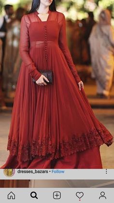 a woman in a long red dress standing on the street