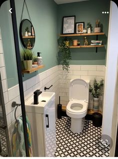 a small bathroom with green walls and black and white tile flooring on the wall