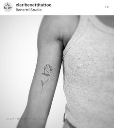 a black and white photo of a woman's arm with a rose tattoo on it