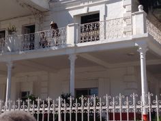 a person standing on the balcony of a white building with balconies and wrought iron railings