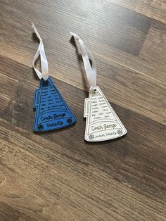 two blue and white luggage tags sitting on top of a wooden table next to each other